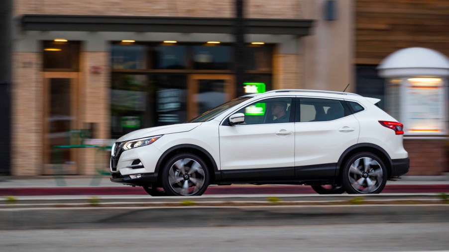 2022 Nissan Rogue Sport travels on a city street past storefronts