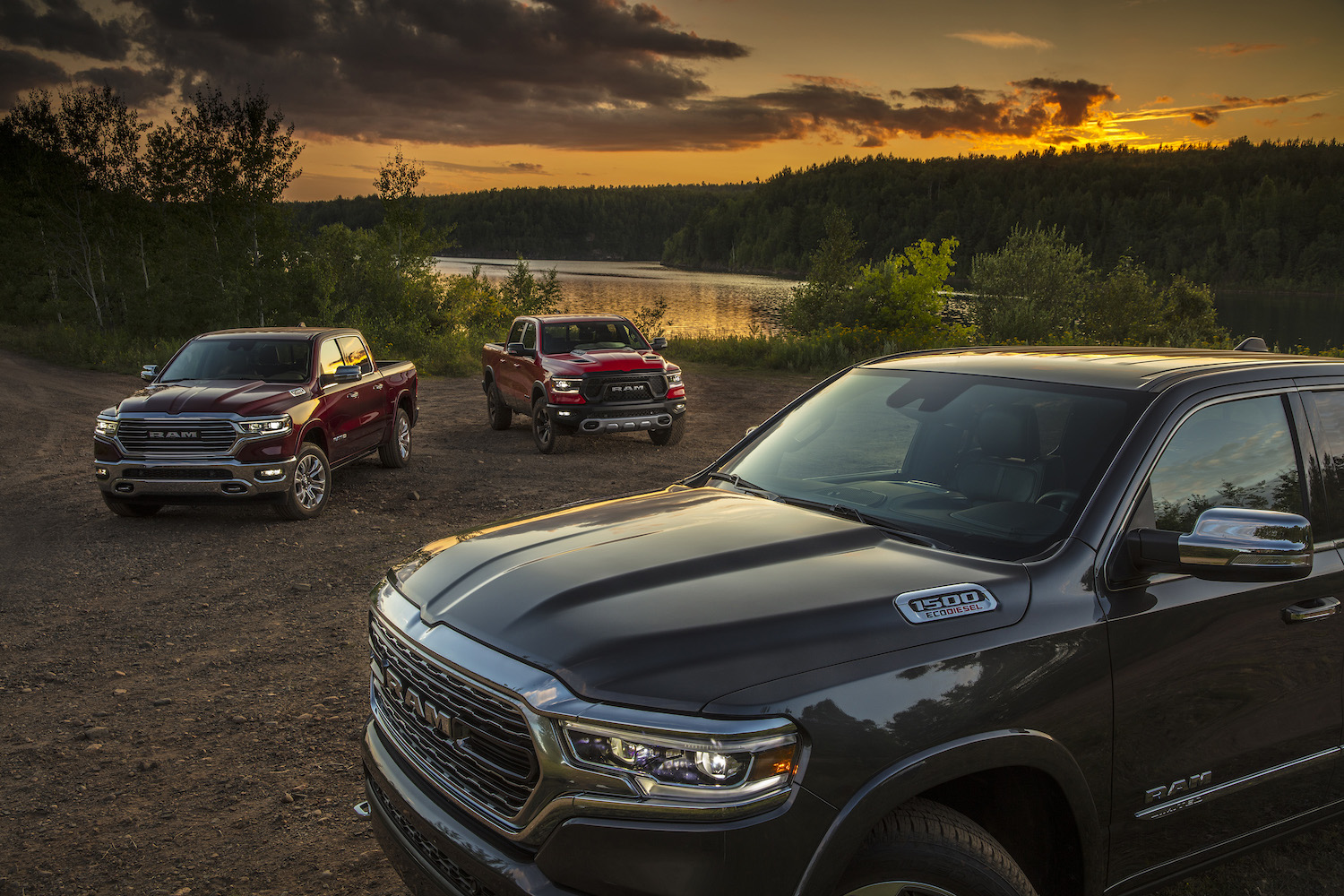 Promo of three 2022 Ram 1500 trucks in front of a pond, EcoDiesel engine badges on display.