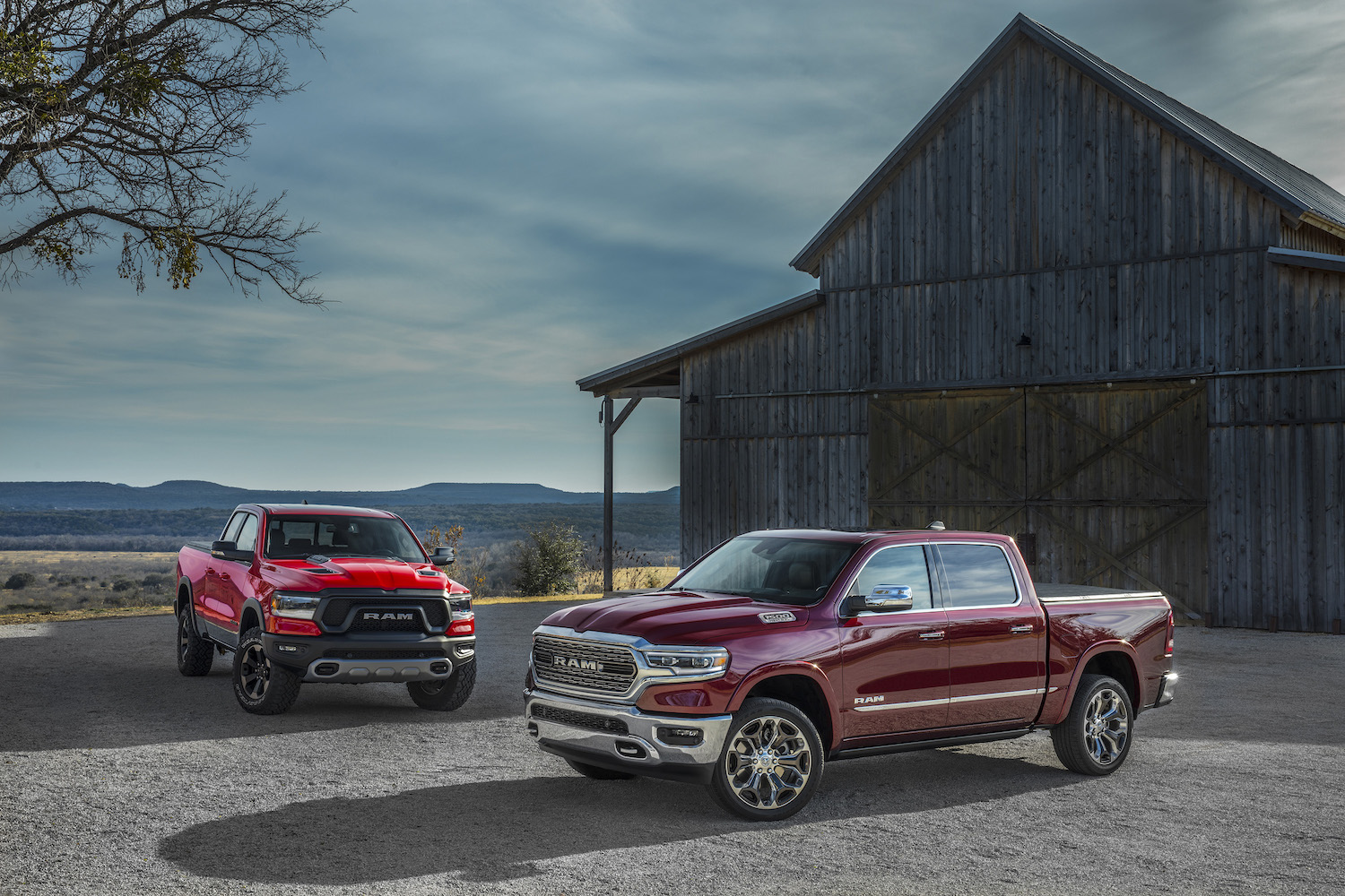 Promo shot of a Ram 1500 Rebel and Limited pickup truck parked in front of a barn.