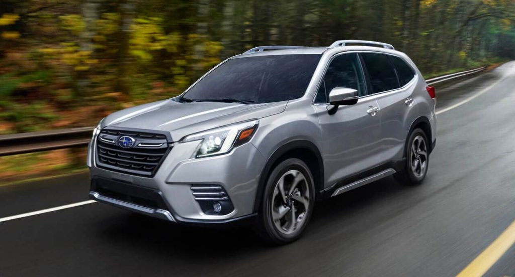 A gray 2022 Subaru Forester compact SUV is driving on the road. 
