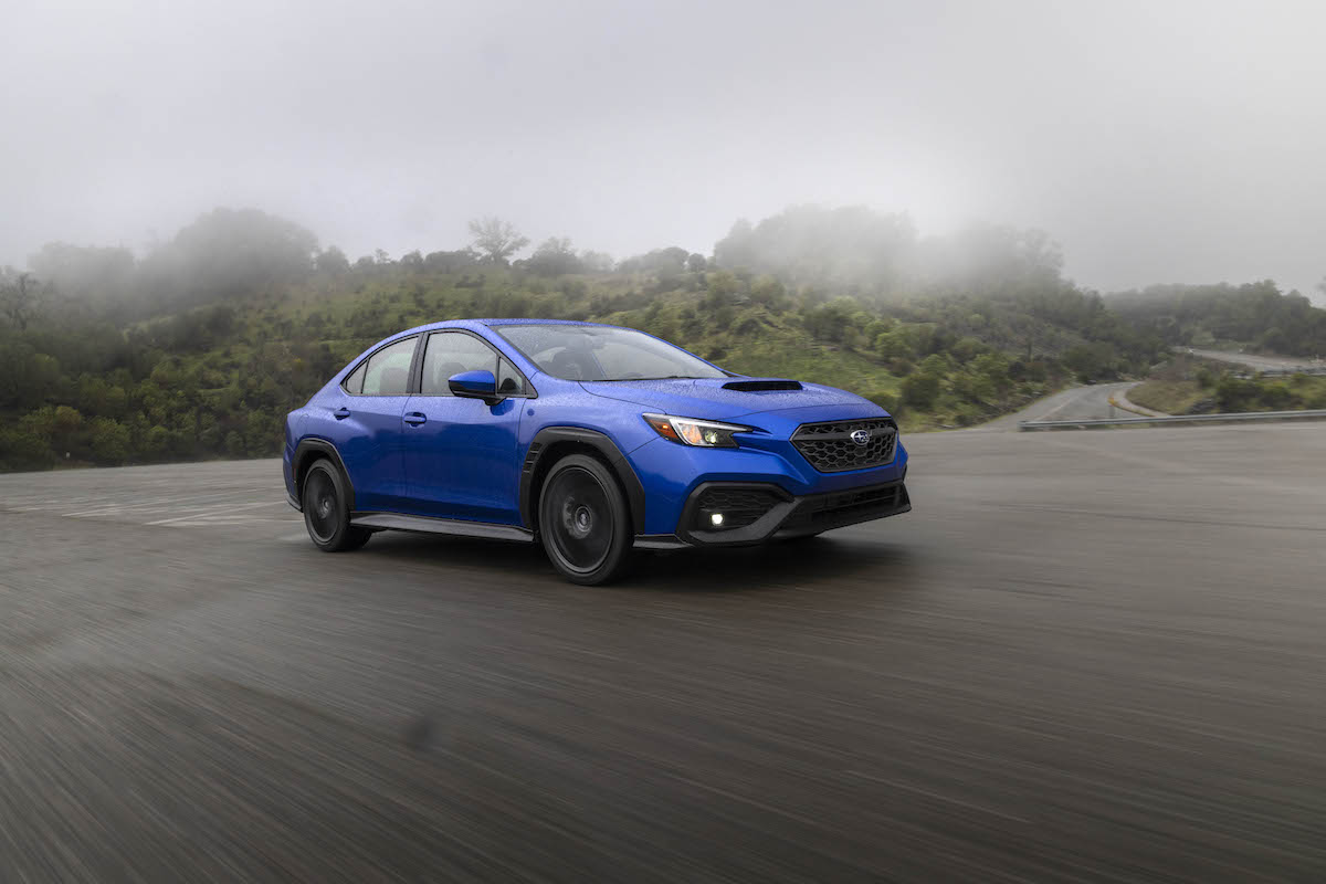 A cobalt-blue 2022 Subaru WRX traveling on a paved stretch in the fog