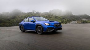 A cobalt-blue 2022 Subaru WRX traveling on a paved stretch in the fog
