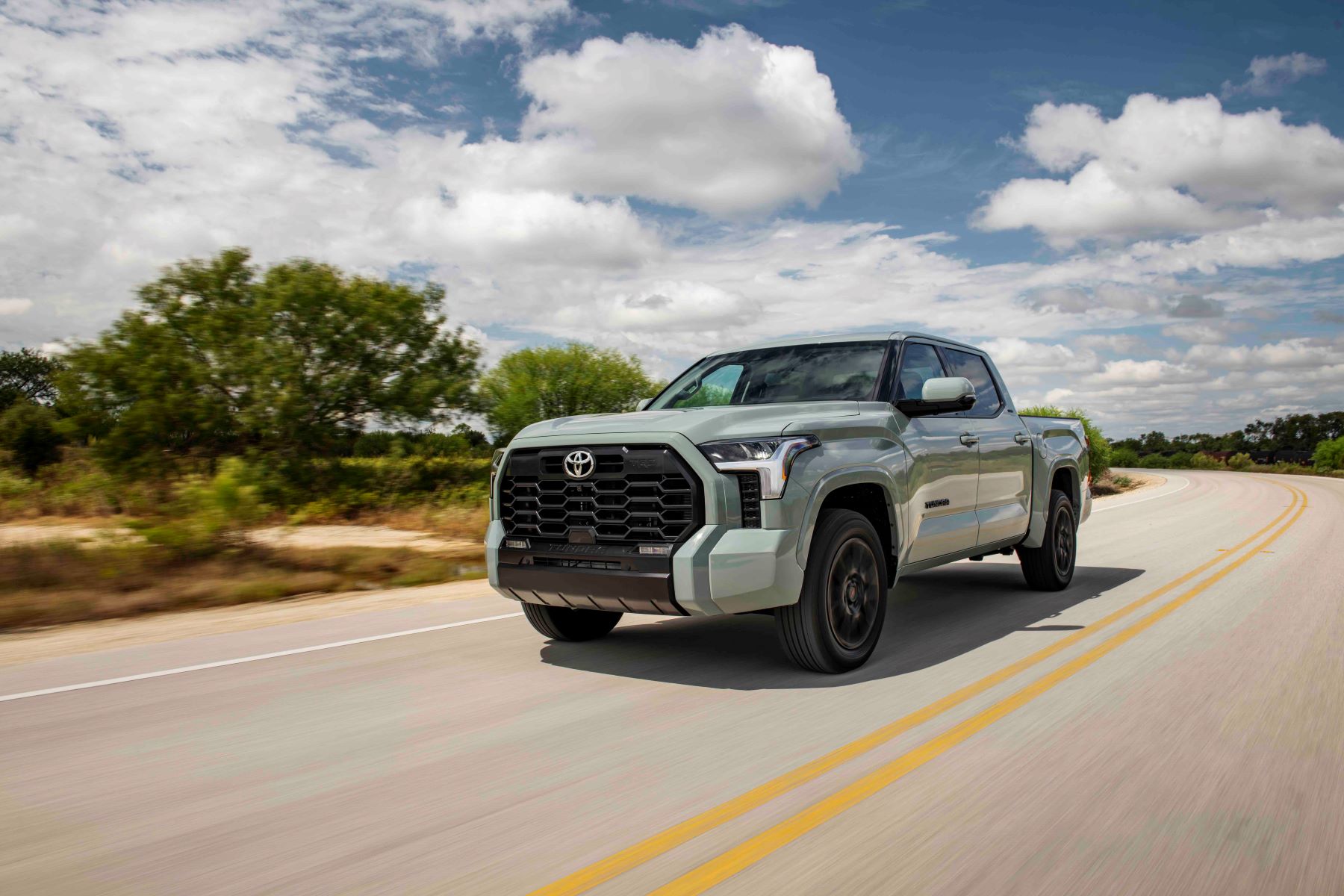 The 2022 Toyota SR5 TRD-Sport full-size pickup truck with Luna Rock paint color option driving down a country highway