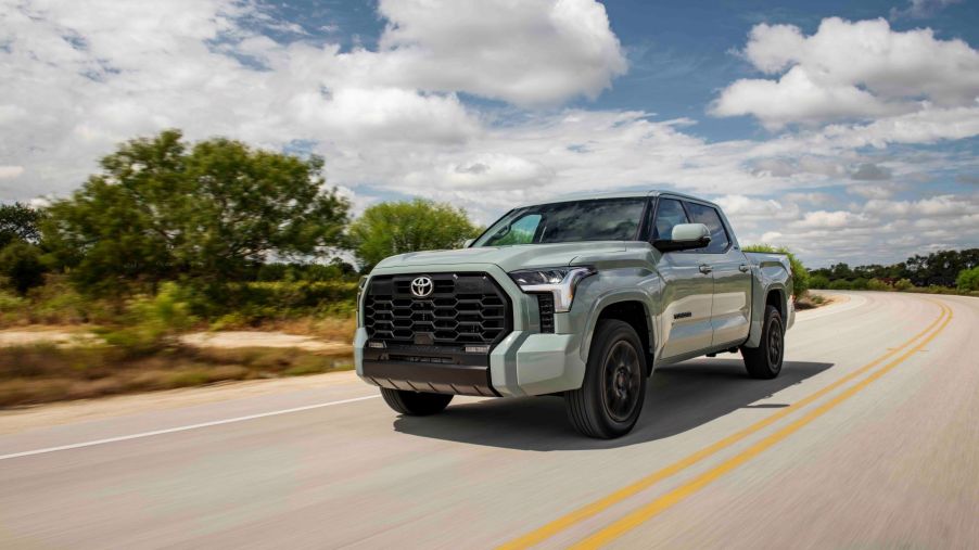 The 2022 Toyota SR5 TRD-Sport full-size pickup truck with Luna Rock paint color option driving down a country highway