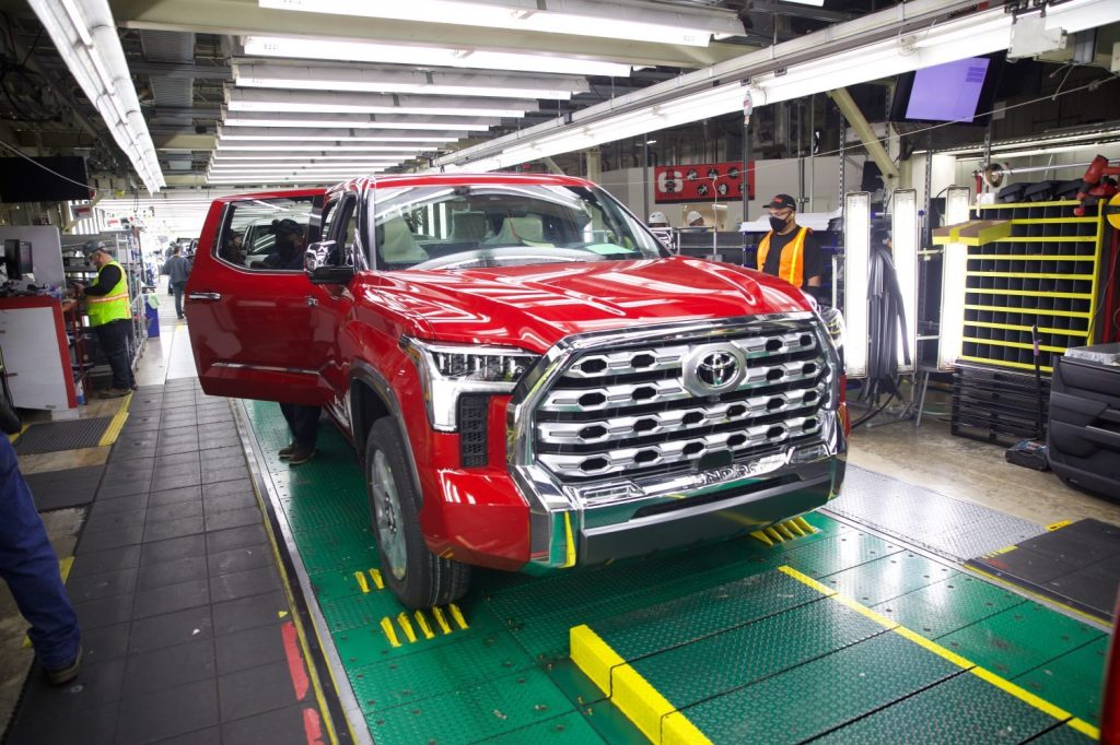 Complete, red Toyota Tundra pickup truck rolling off the end of the assembly line.