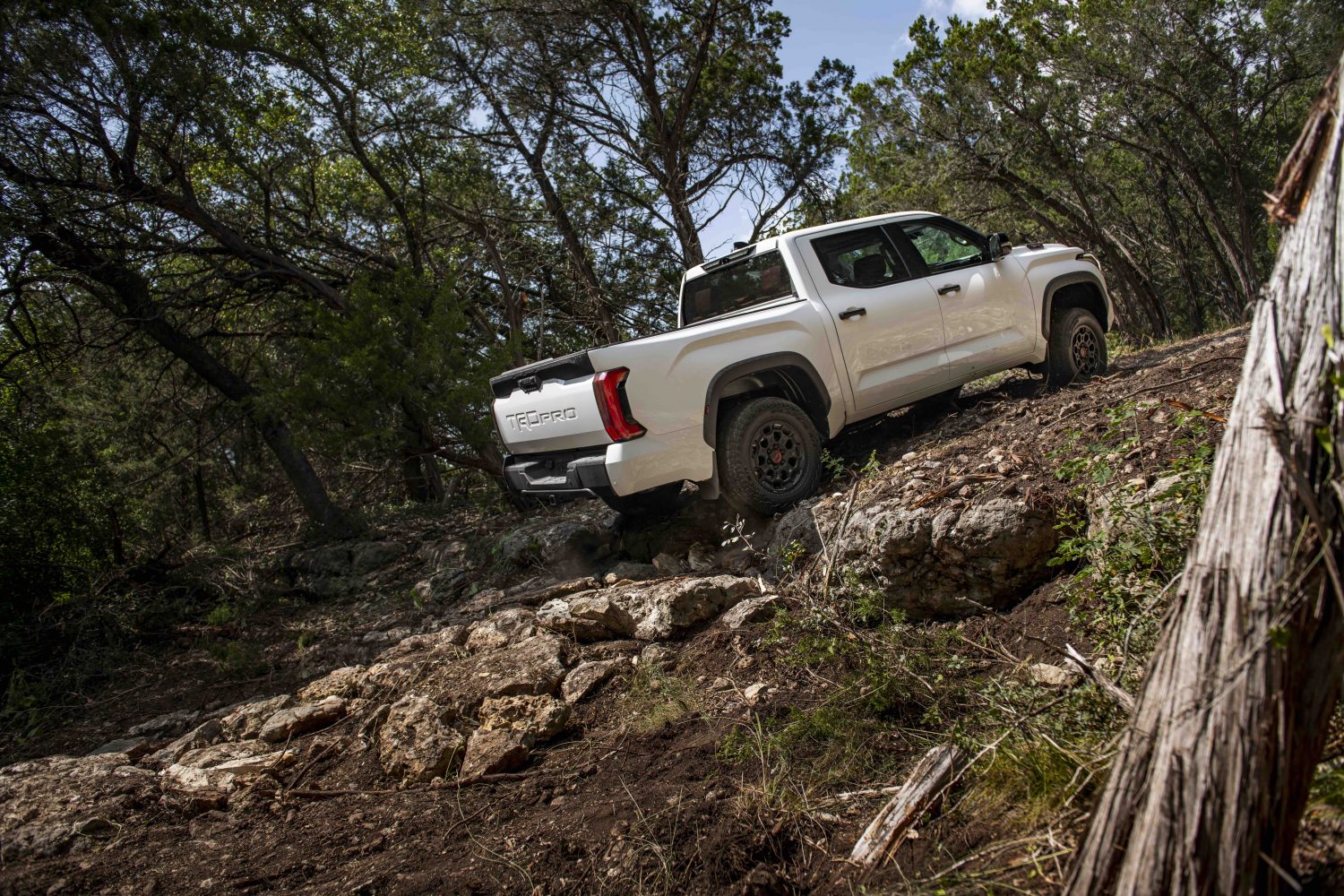 Promo of a 2022 Toyota Tundra pickup truck off road, climbing up a pile of rocks.