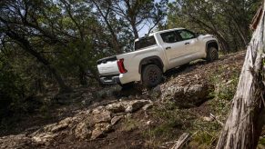 Promo of a 2022 Toyota Tundra pickup truck off road, climbing up a pile of rocks.