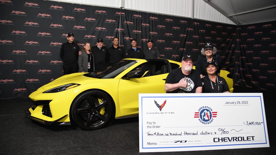 A yellow 2023 Chevrolet Corvette shot with a check made out to charity Operation Homefront