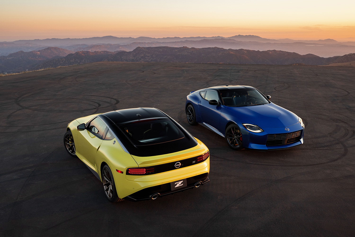 two 2023 Nissan Z Sports Coupe models sitting side by side front and rear sunset 