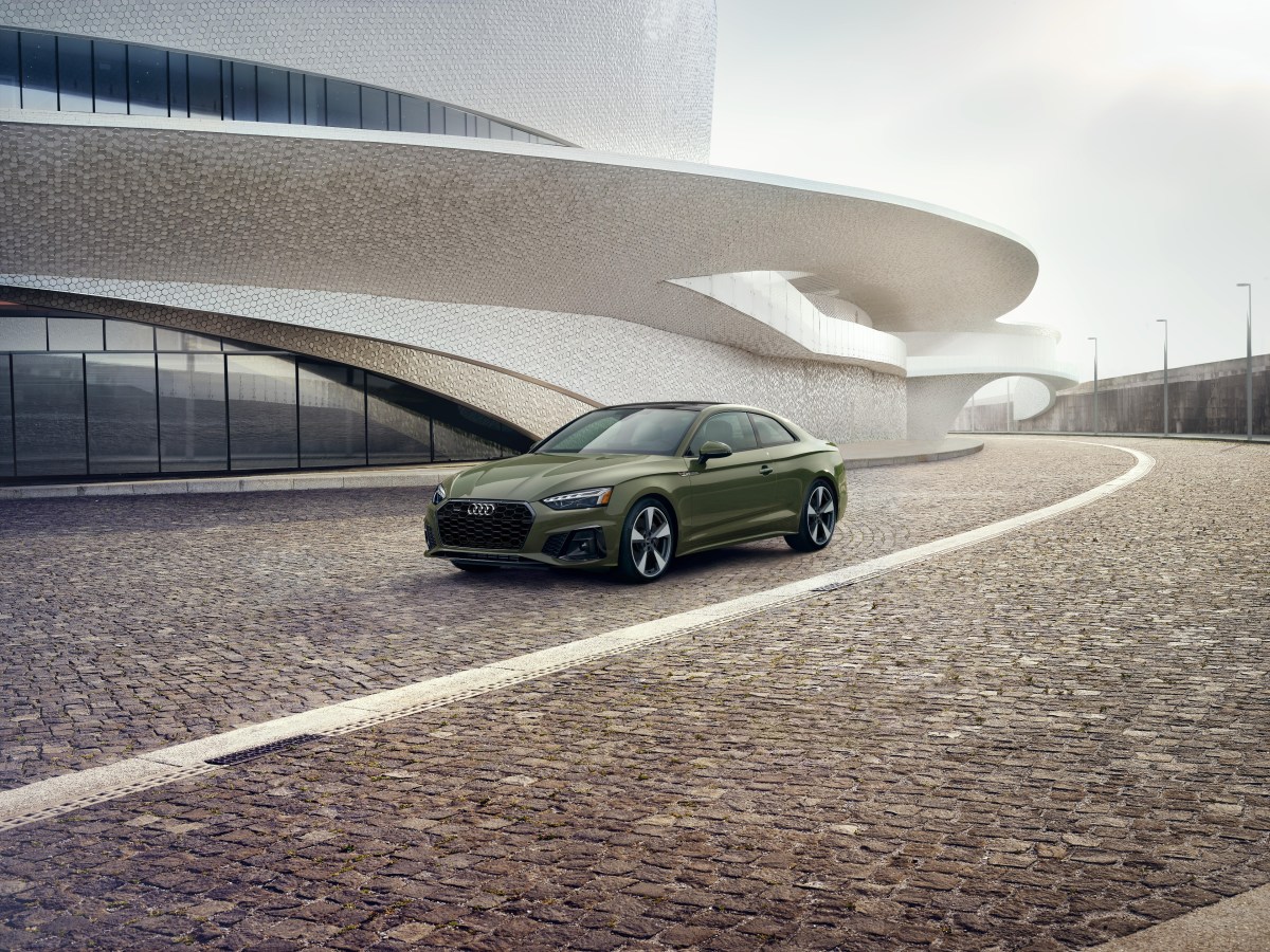 A 3/4 front view of a 2020 Audi A5 Coupe in green, parked in front of a white building.