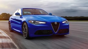 A 3/4 front view of a blue 2022 Alfa Romeo Giulia sedan driving on a race track