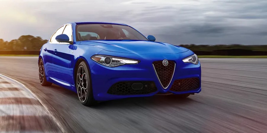 A 3/4 front view of a blue 2022 Alfa Romeo Giulia sedan driving on a race track