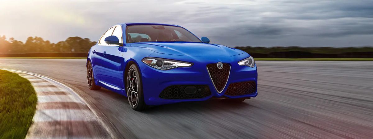 A 3/4 front view of a blue 2022 Alfa Romeo Giulia sedan driving on a race track.
