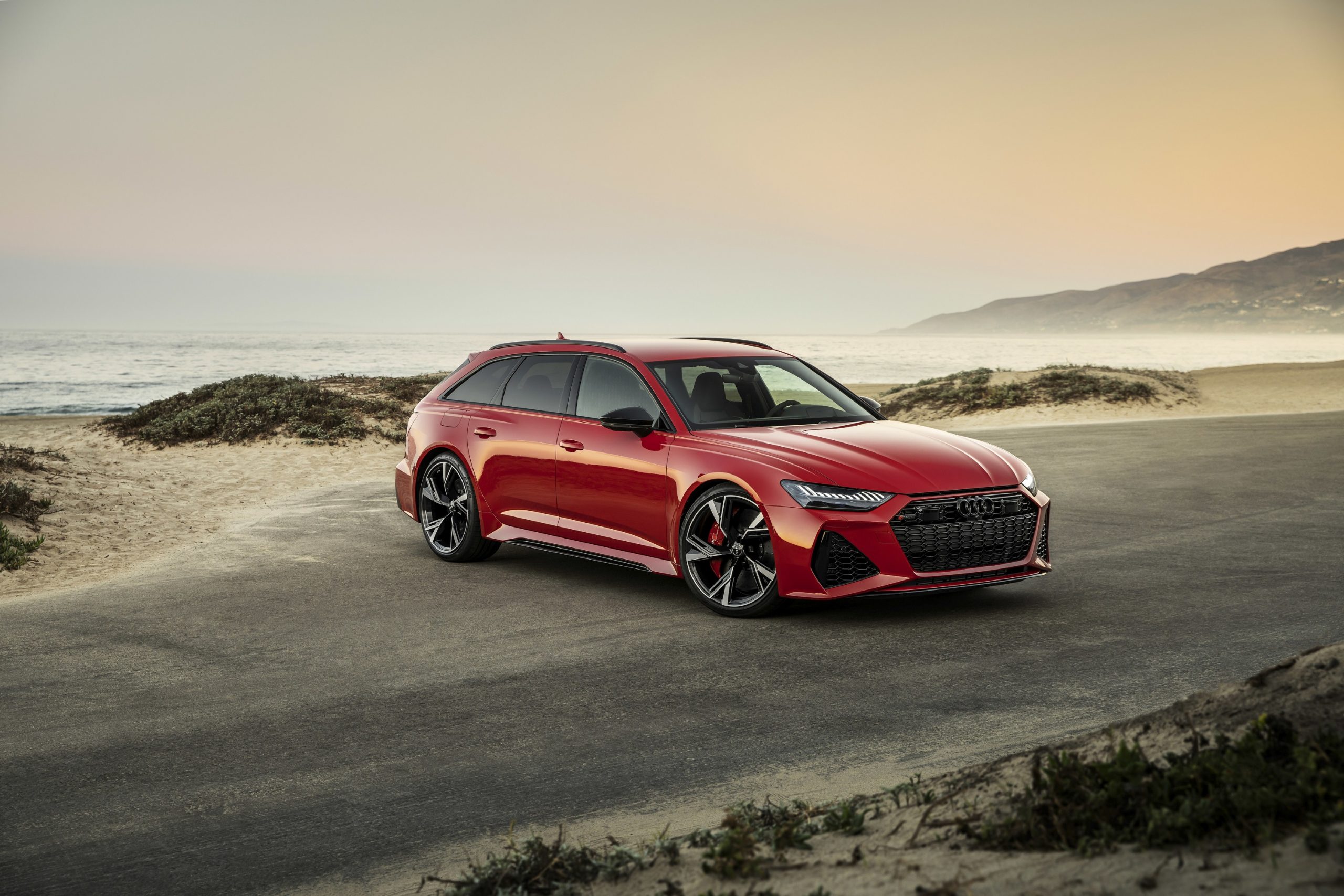 A red Audi RS6 Avant shot from the front 3/4 on a beach