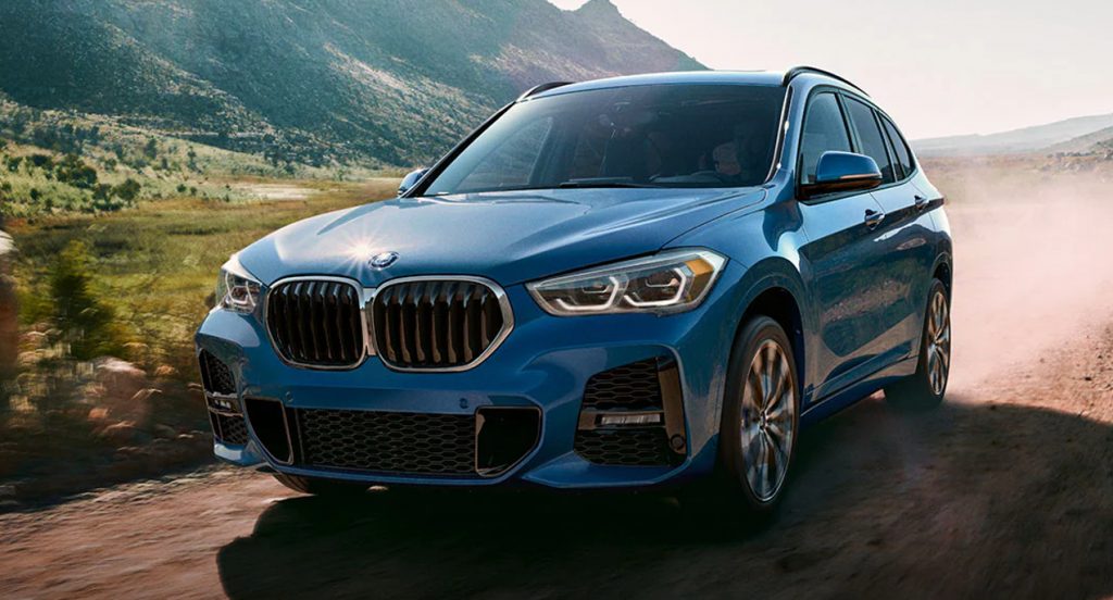 A blue 2022 BMW X1 luxury SUV is driving off-road. 