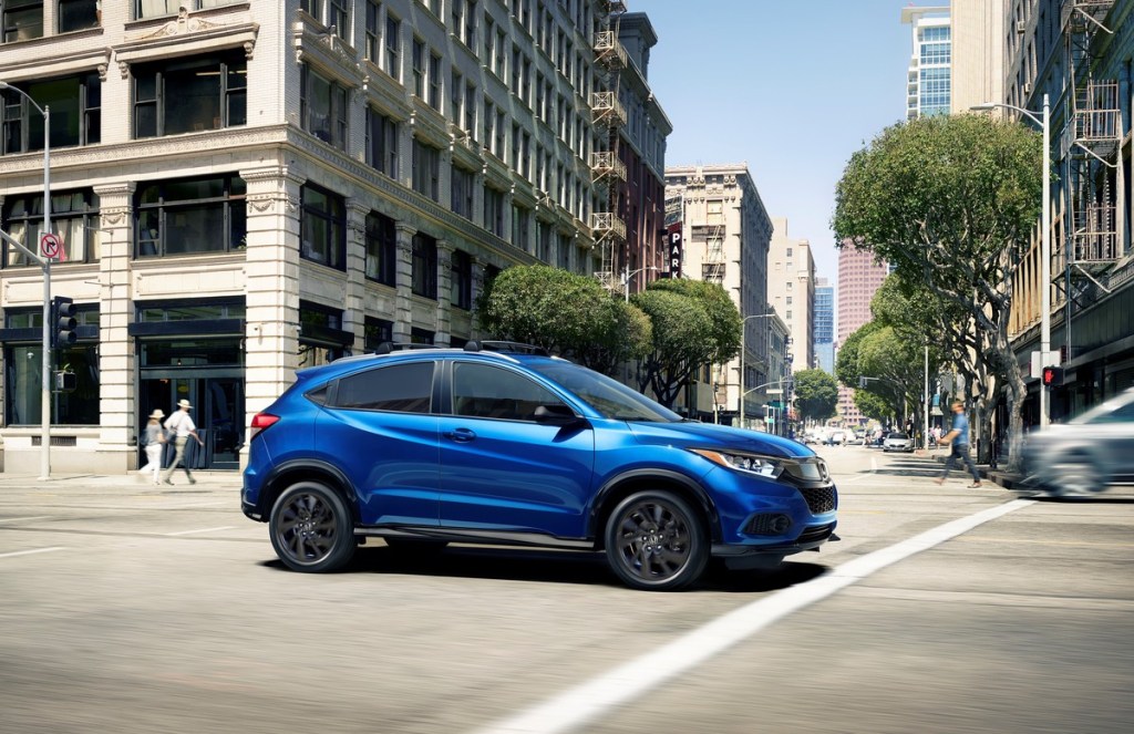 Blue 2022 Honda HR-V driving by a large building