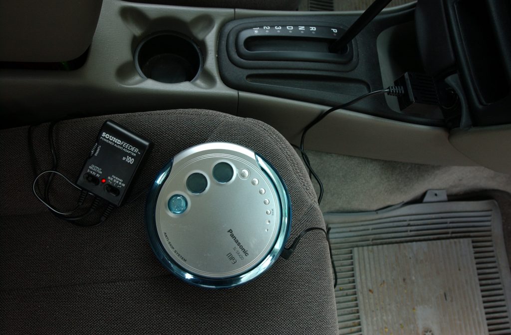 A portable CD player plugged into a car radio.