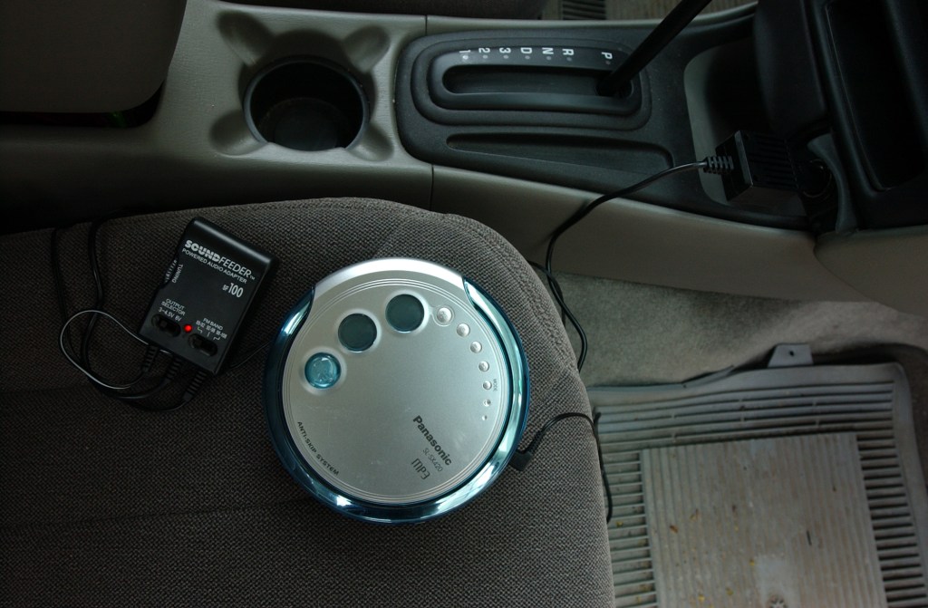 A portable CD player plugged into the car radio.