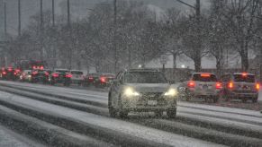 A main car driving with cars driving in the opposite direction at night while driving in winter conditions.