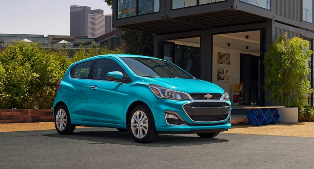 A blue Chevy Spark small car is parked. 