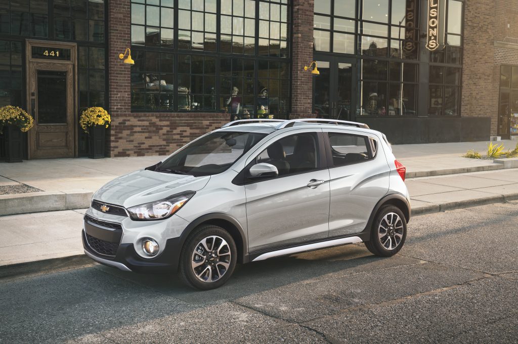A silver Chevy Spark shot from the 3/4 angle on a city street