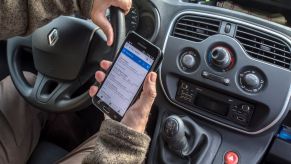 A man being a distracted driver by watching his phone rather than the road, which is a bad driving habit.