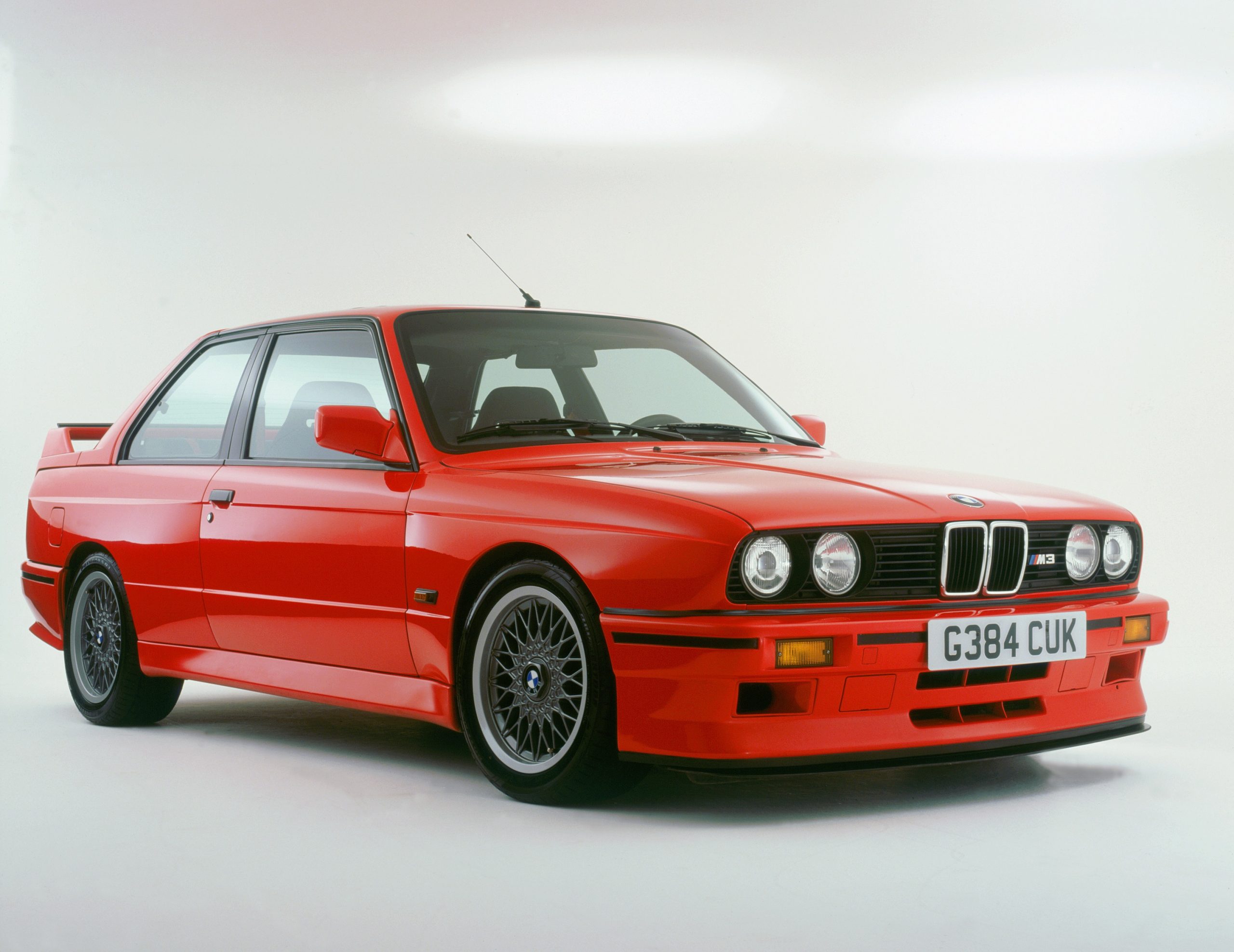 A red E30 BMW M3 sports car shot from the front 3/4