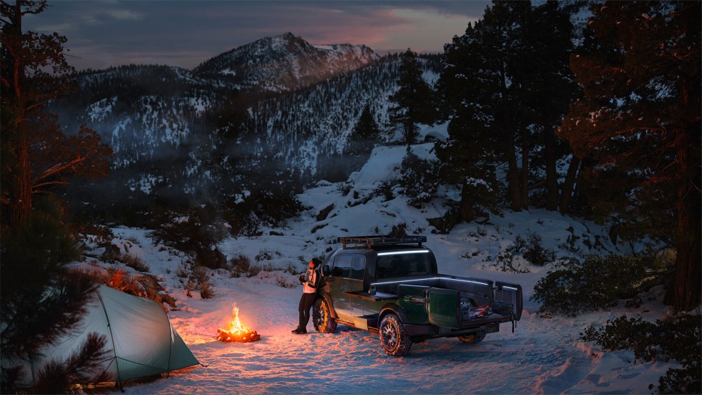 Electric green 2023 Canoo Pickup Truck parked near a campfire, highlighting its release date and price