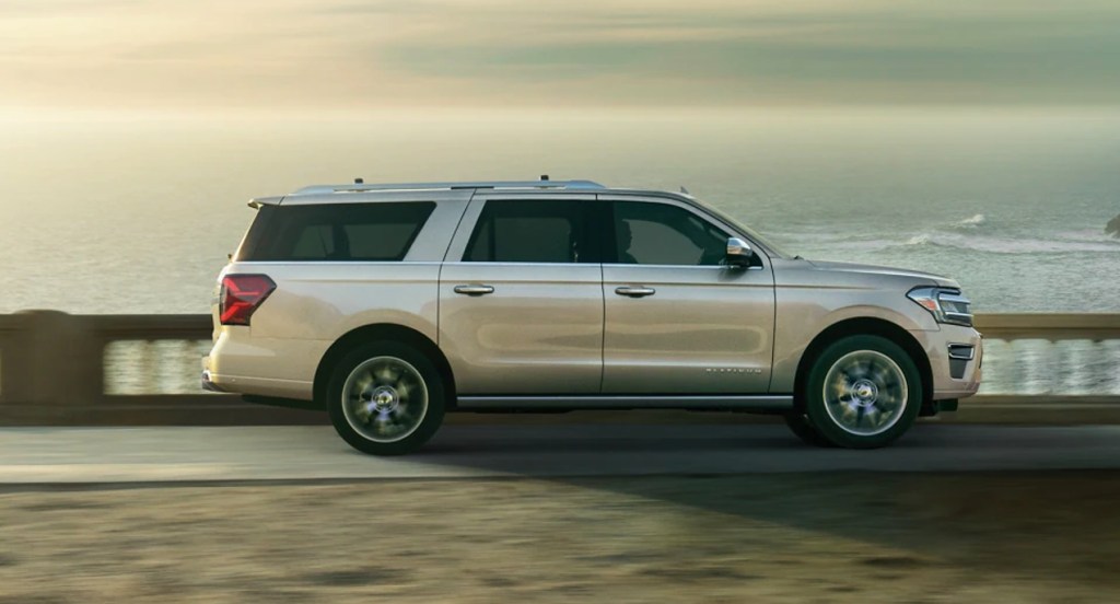 A gray Ford Expedition is driving next to the ocean. 