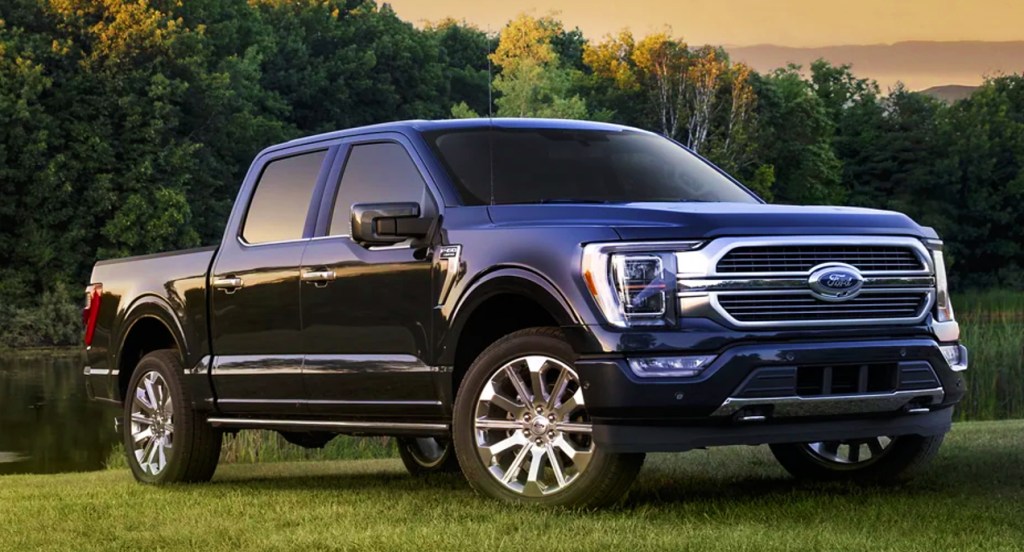 A blue 2022 Ford F-150 full-size pickup truck is parked on grass. 