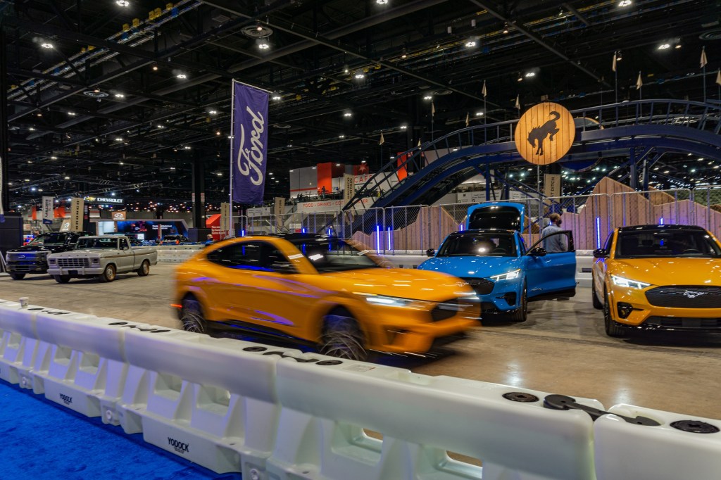 A black Ford F-150 Lightning, gray F-100 Eluminator, and several Mustang Mach-Es at the 2022 Chicago Auto Show test track