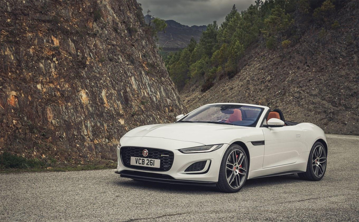Jaguar F-Type Convertible top down on mountain road displaying front driver angle