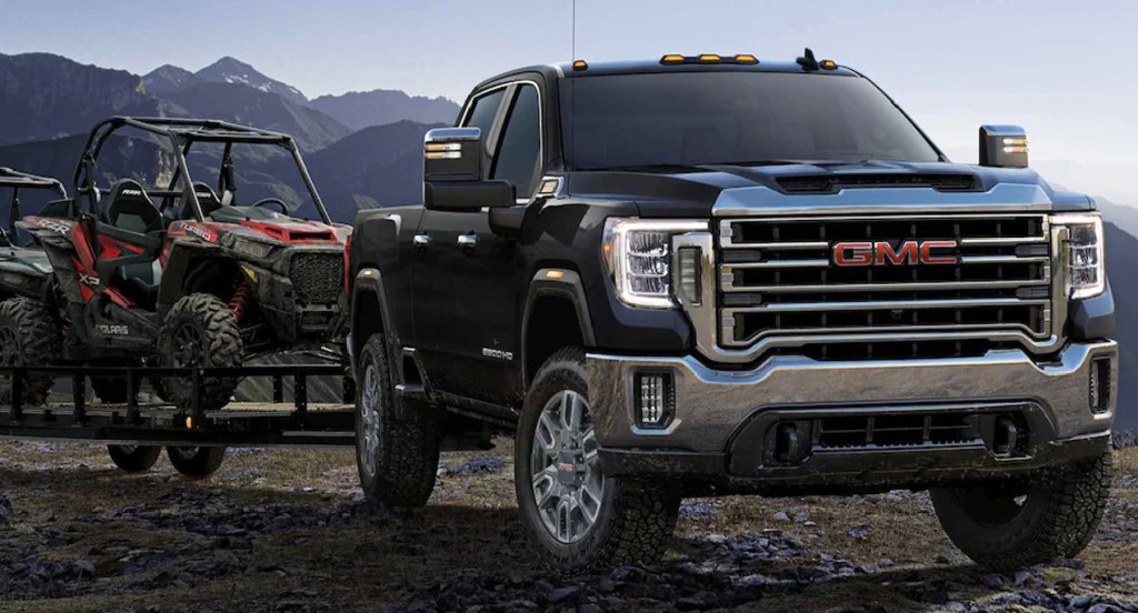 A black 2022 GMC Sierra 3500 HD Denali heavy duty pickup truck is towing a four-wheeler. 