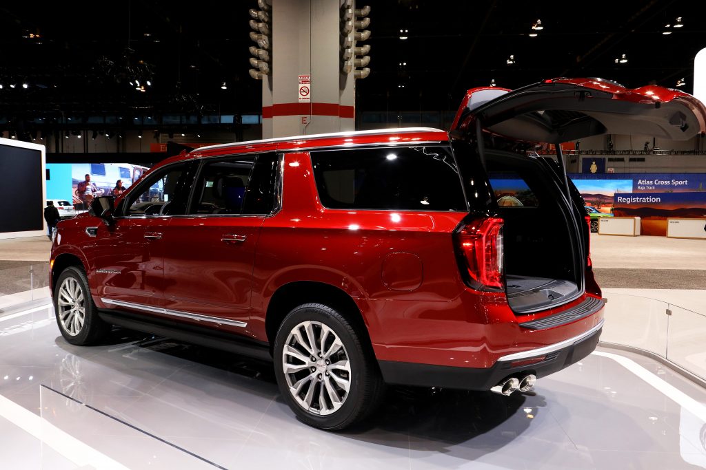 A red GMC Yukon SUV on a show floor with the rear door open and shows off a spacious interior.