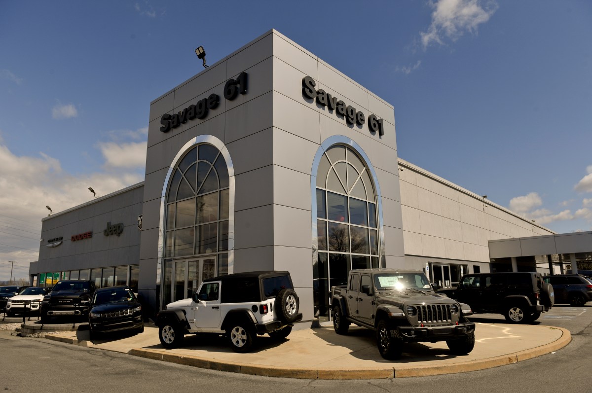 An image of the front of Savage 61 Chrysler Dodge Jeep Dealership. The images show the building and a selection of Jeeps parked in front.