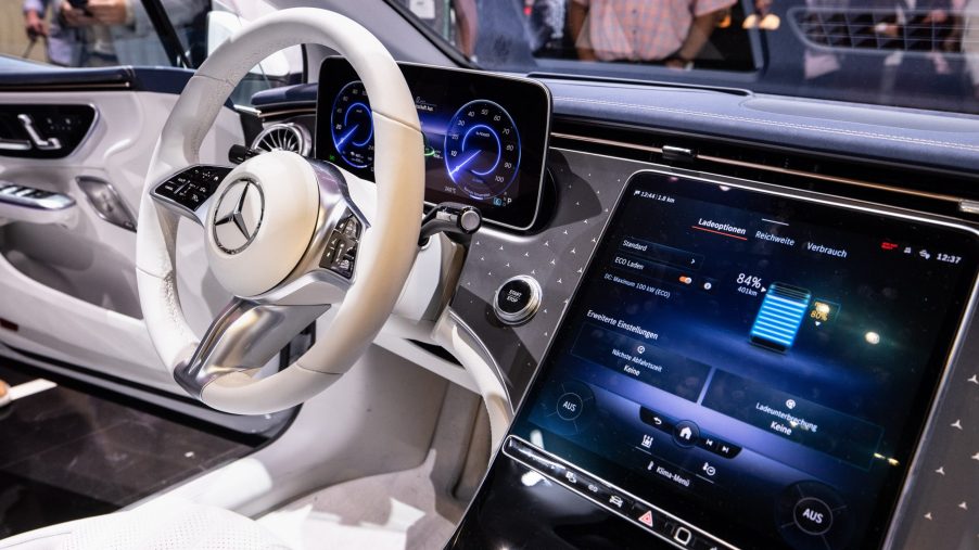 An interior view of a Mercedes-Benz EQS showing the steering wheel, dashboard and infotainment display.