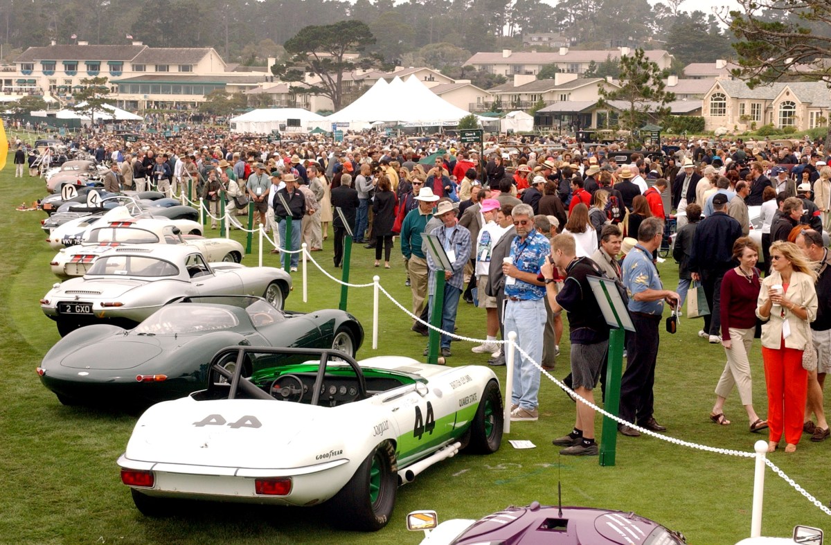 A view of classic Jaguars lined up with a large crowd at the Pebble Beach Concours.