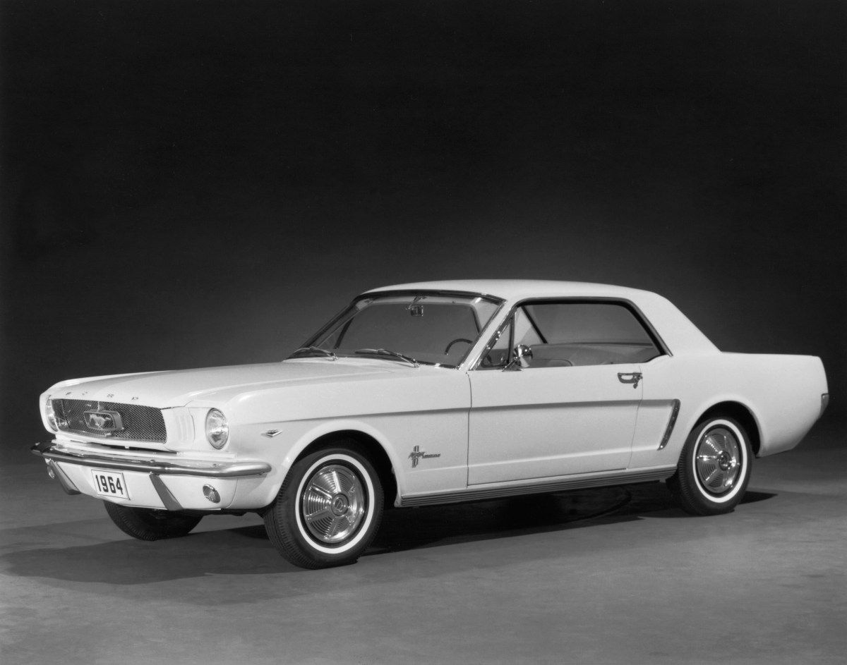 A black and white photo of a 1964 Ford Mustang coupe on display at the  New York World's Fair.