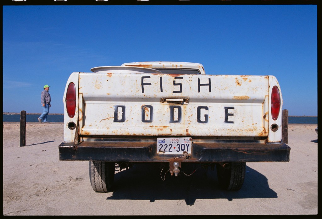 A high mileage white Dodge Ram pickup truck parked on a beach in Texas