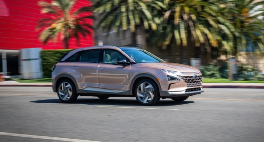 A Copper Metallic Hyundai Nexo compact SUV is driving on the road. 