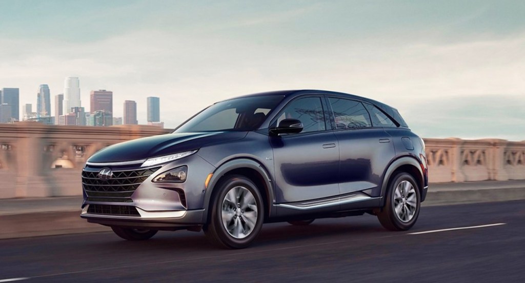 A 2022 Dusk Blue Hyundai Nexo compact SUV is driving on the road.