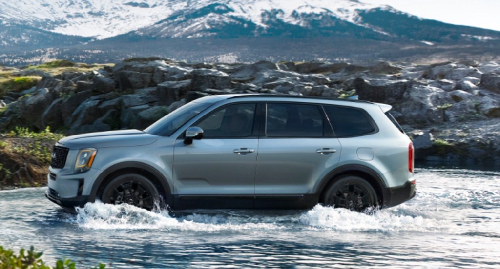 A gray 2022 Kia Telluride is driving through shallow water.