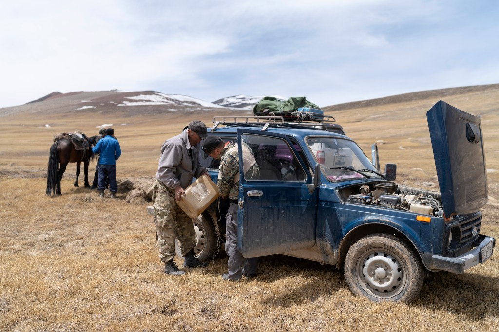 Two individuals work on their Lada Niva in a remote location.