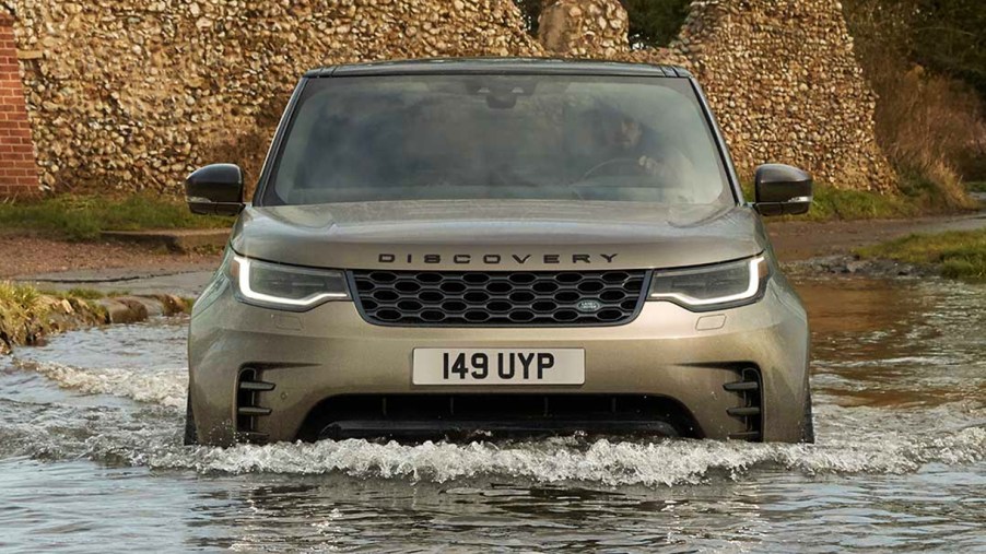 A gray Land Rover Discovery is driving in water.