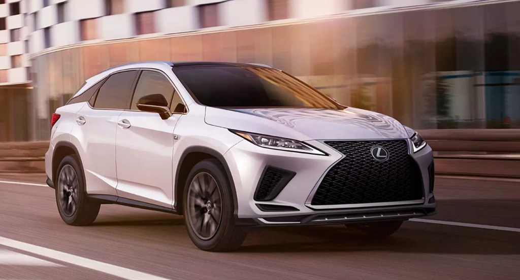 A white 2022 Lexus RX L midsize luxury SUV is driving on the road. 