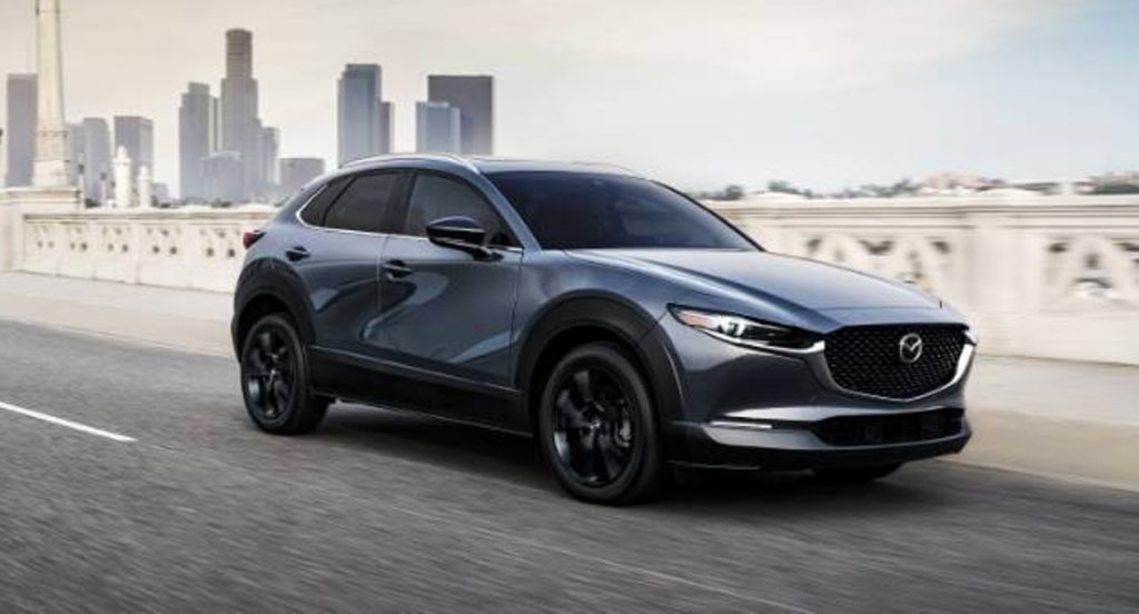 A gray 2022 Mazda CX-30 small SUV is driving on the road. 