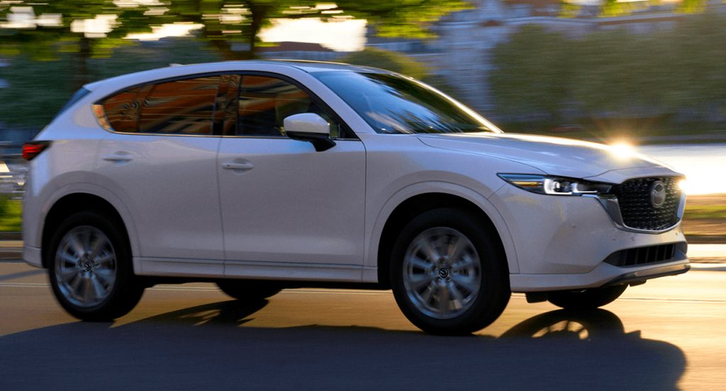 A white Mazda CX-5 is driving on the road. 