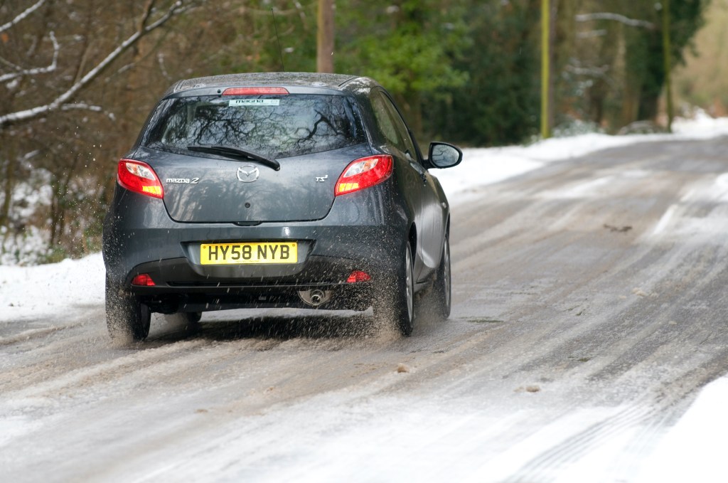 2009 Mazda 2 driving on a snowy road.