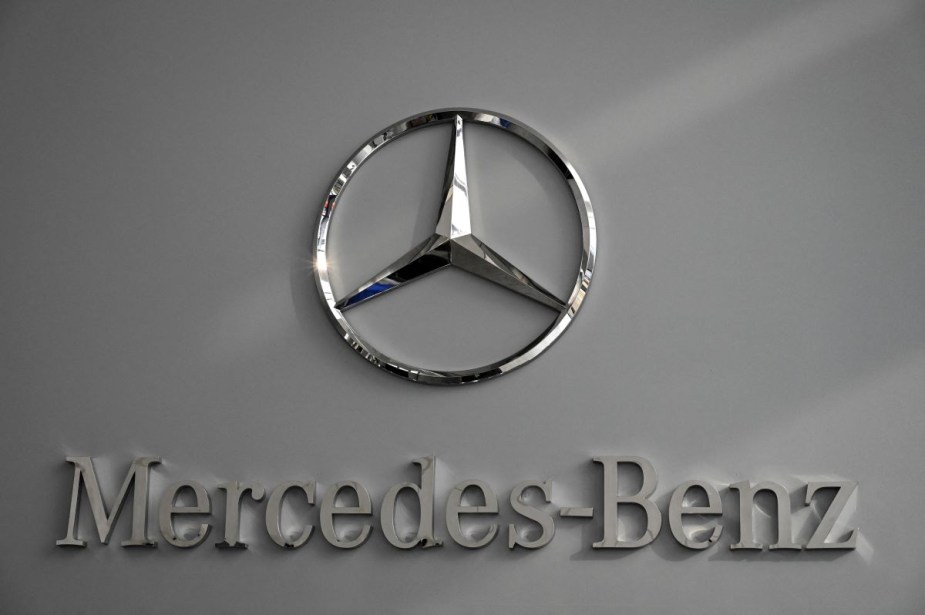 A chrome Mercedes-Benz logo on a gray background. 