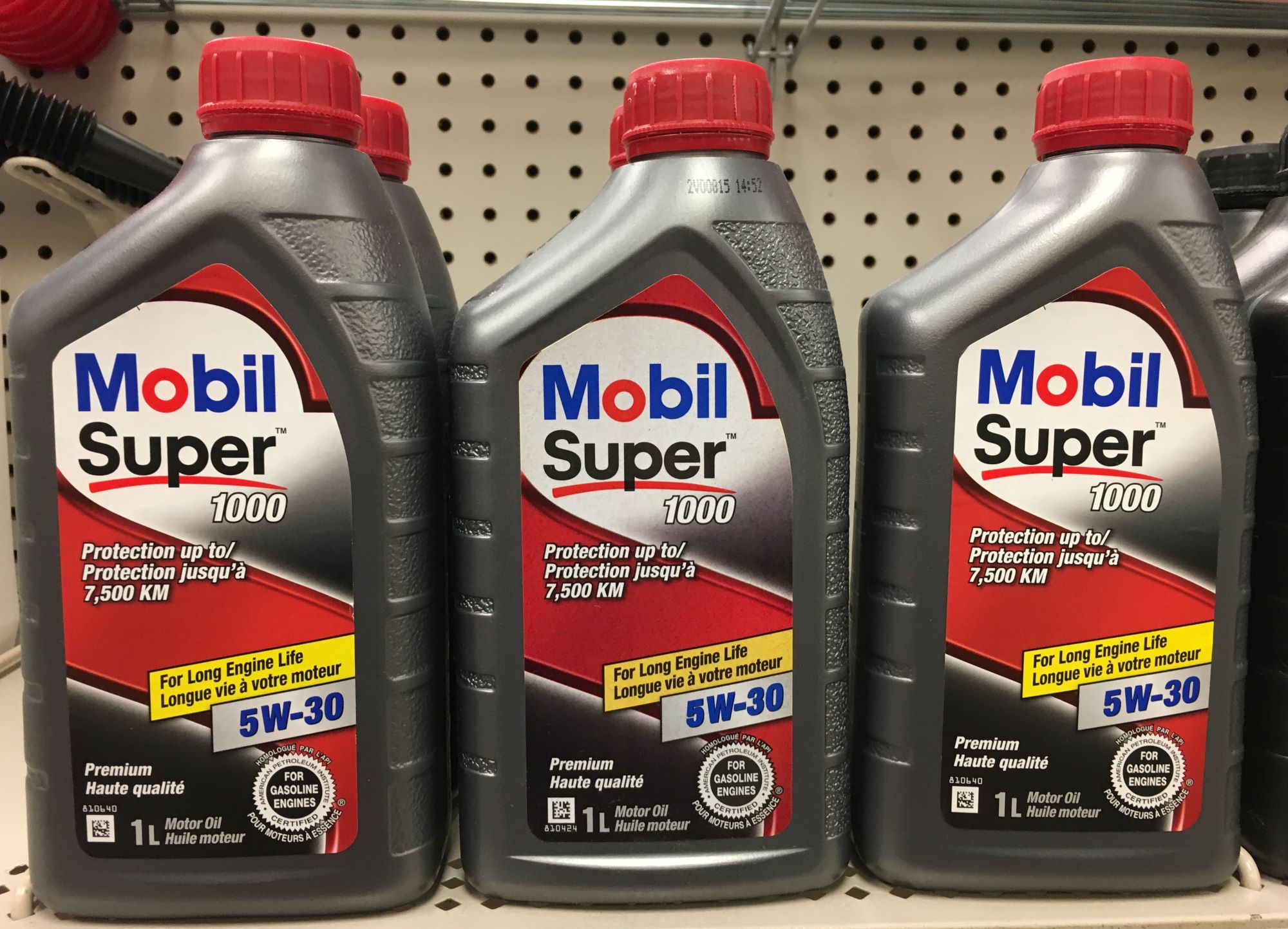 Three bottles of motor oil, such as synthetic, natural, or a mix, sitting on a shelf.
